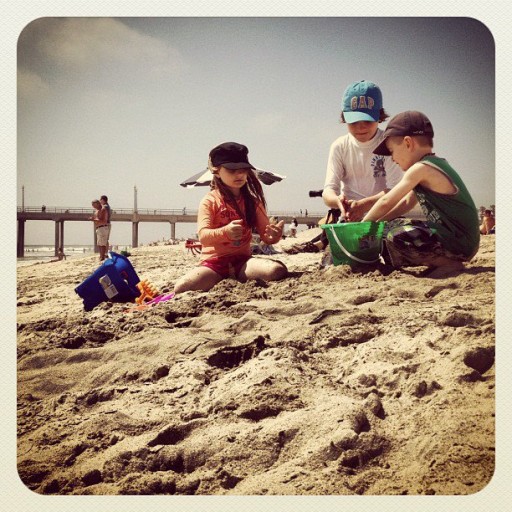three kids playing and enjoying the sand at the beach