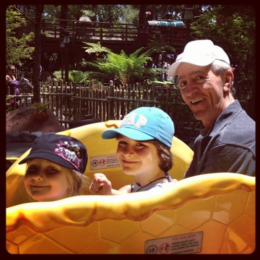 girl and boy siblings enjoying the ride in Disneyland together with their grandfather
