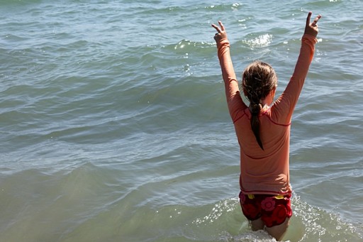 young girl in the sea water with two arms up