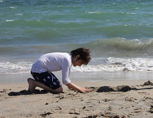 young boy playing in the sand near the sea water