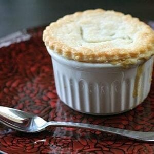 Mini Chicken Pot Pies in white ramekins on a red rose designed plate with spoon