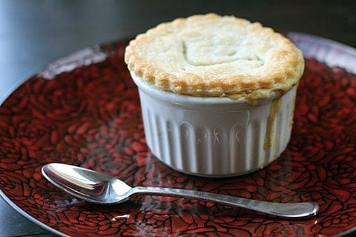 Mini Chicken Pot Pies in white ramekins on a red rose designed plate with spoon