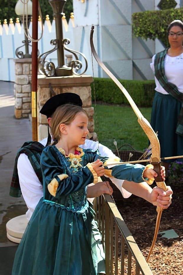 little girl in green dress doing some target shooting at Disney