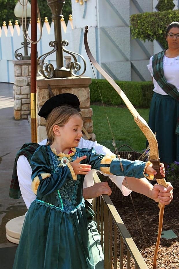 little girl closes her eyes when shooting the arrow