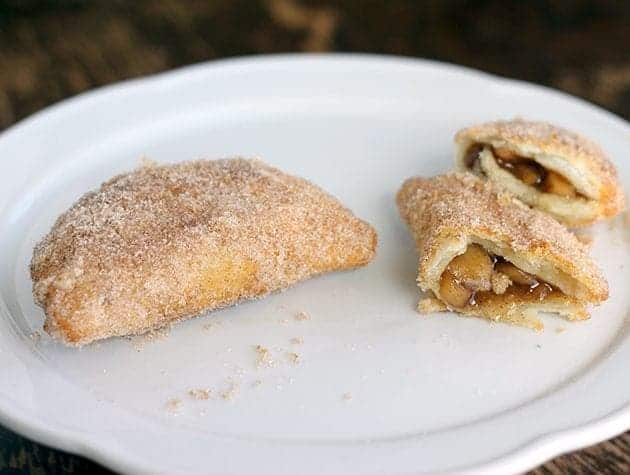 Mini Apple Fried Pies in white plate, one pie broke into half showing the filling inside it