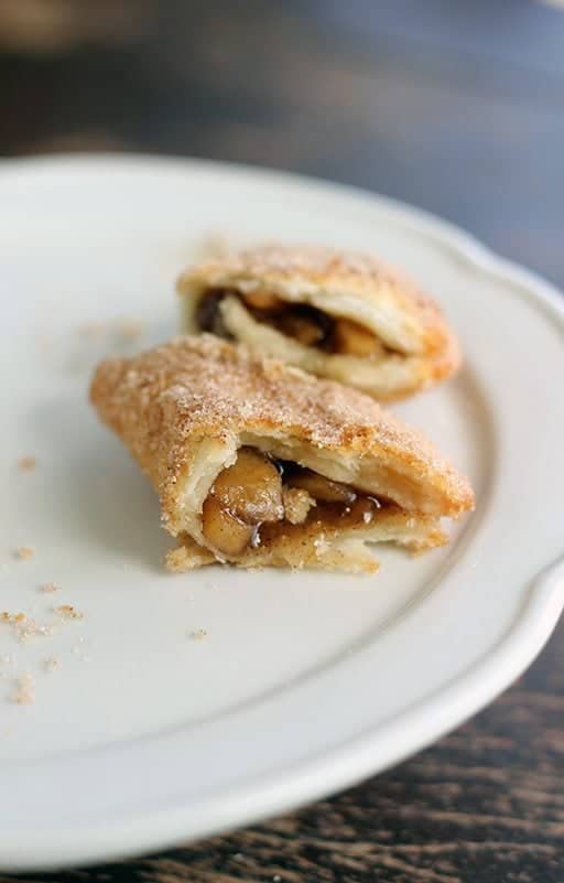 Mini Apple Fried Pies in white plate broke into half showing the filling inside it