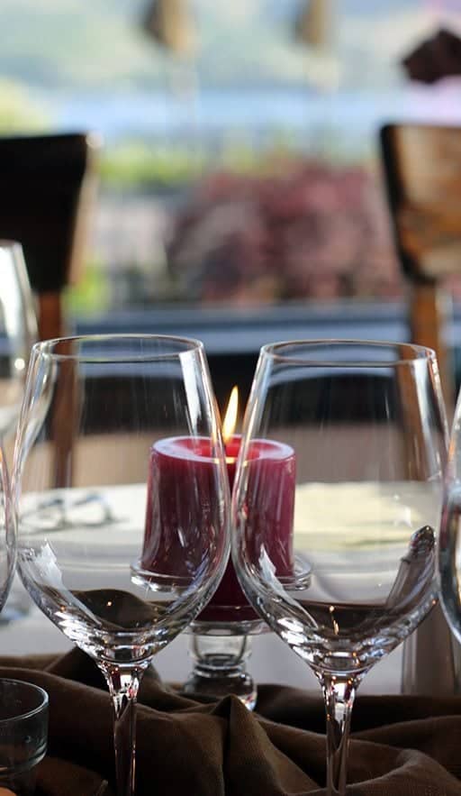 close up of wine glasses and red lighted candles