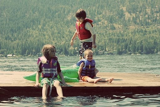 three kids having fun on a dock in the lake