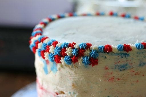 adding more layers of star shape icing to the cake in alternate color of blue, red and white