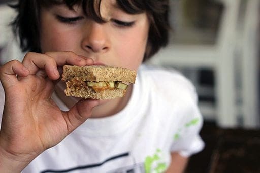 little boy having a bite of sweet peanut butter and pickle sandwich