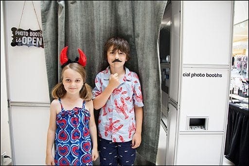 two kids outside the photo booth wearing props