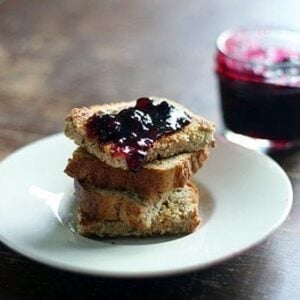 close up of Saskatoon Berry Jam on top of toast in a white plate and on a jar beside it