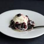 Saskatoon Berry Sauce in a white plate, topped with vanilla ice cream