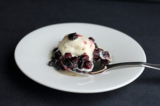 Saskatoon Berry Sauce in a white plate, topped with vanilla ice cream
