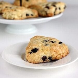 close up slices of White Chocolate Saskatoon Berry Scones in white plate and in cake holder