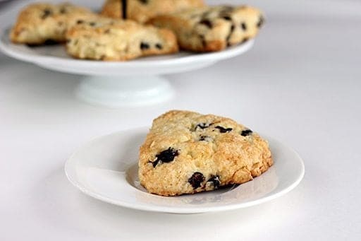 close up slices of White Chocolate Saskatoon Berry Scones in white plate and in cake holder