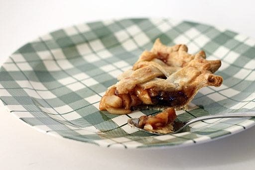 a slice of Amaretto Raisin Crabapple Pie in a checkered green plate with a spoon