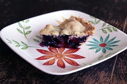 close up slice of Blueberry Rhubarb Pie in a white plate with floral design