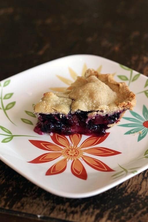 close up slice of Blueberry Rhubarb Pie in a white plate with floral design