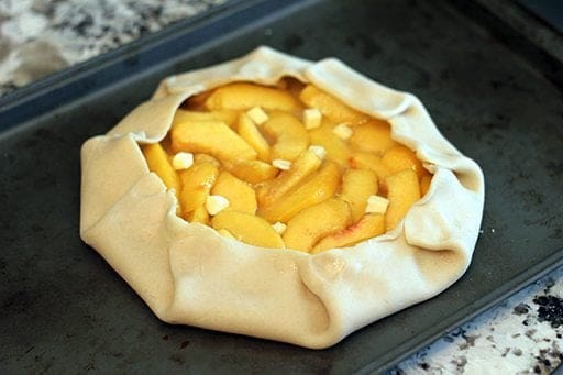 Peach Galette pastry with peach mixture in the center with dots of butter