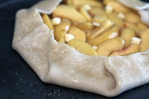 Peach Galette pastry with peach mixture brushed with egg and rum mixture and sprinkled with brown sugar