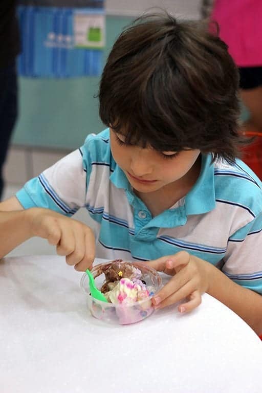 little boy enjoying his frozen yogurt in a cup with chocolate and sprinkles