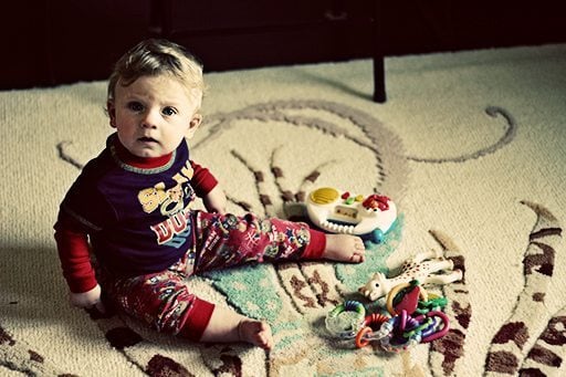cute little baby boy on the mat with his toys