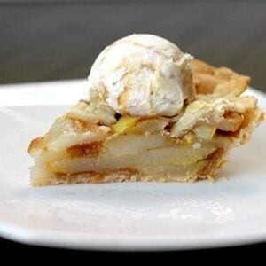 close up slice of Pear Pie in a white plate topped with a scoop of ice cream