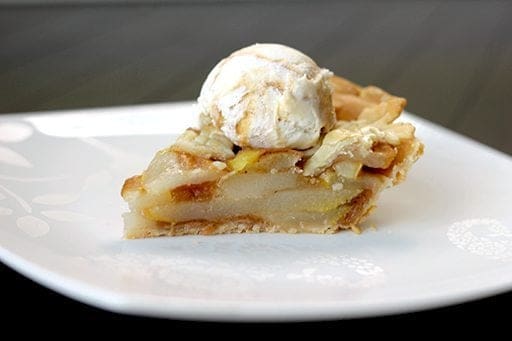 a slice of Pear Pie in a white plate topped with a scoop of ice cream