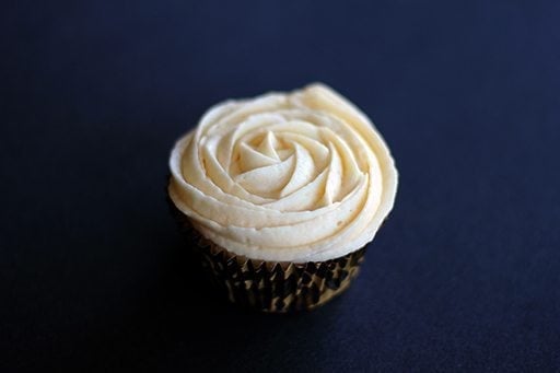 The Best Buttercream Icing on top of cupcake on dark background