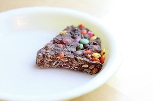 a slice of Leftover Halloween Candy Pie in a white shallow pie dish