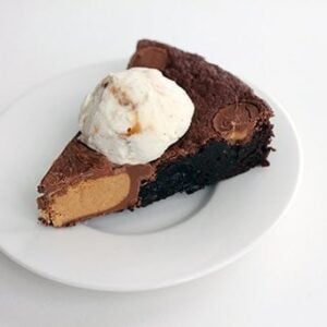 a slice of Giant Reese's PB Cup Skillet Brownie topped with a scoop of vanilla ice cream