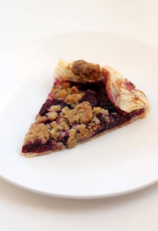 slice of raspberry galette with walnut struesel topping in a white plate