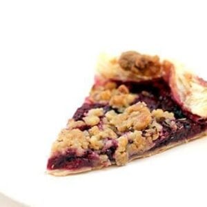 slice of raspberry galette with walnut struesel topping in a white plate