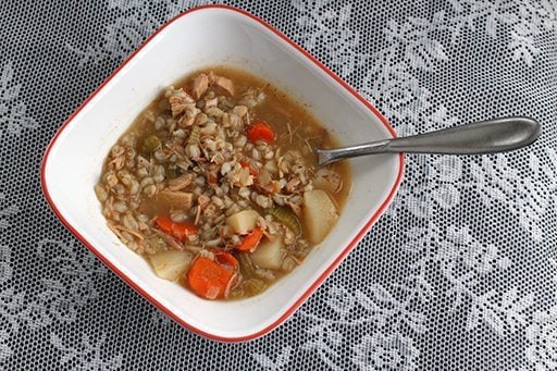 Chicken Barley Soup in a red large bowl with a spoon