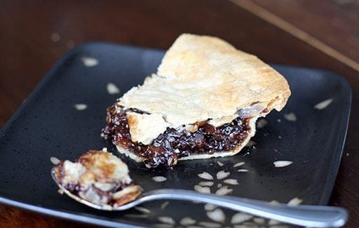 a slice of mincemeat pie in a black plate with a spoon 