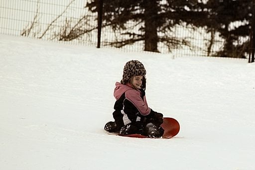 young girl in red sled started to slide in the snow
