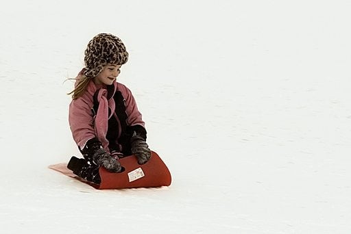 young girl in her red sled