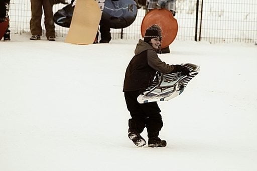 young boy setting up his sled in the snow
