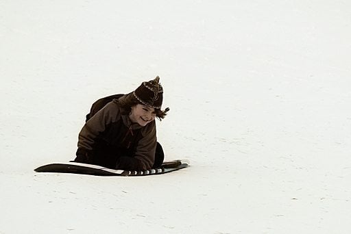 young boy sledding over snow