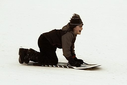 young boy enjoys sledding over snow on a sled