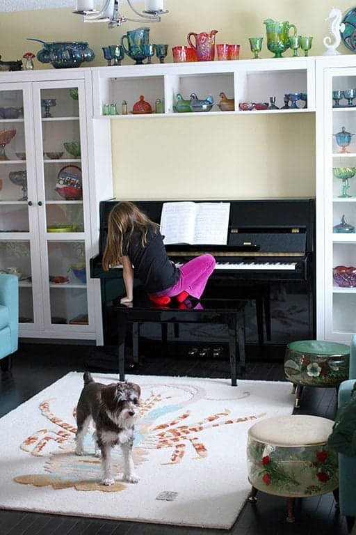 young girl sitting in front of piano, a dog on a carpeted floor