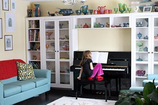young girl sitting in front of piano and playing it