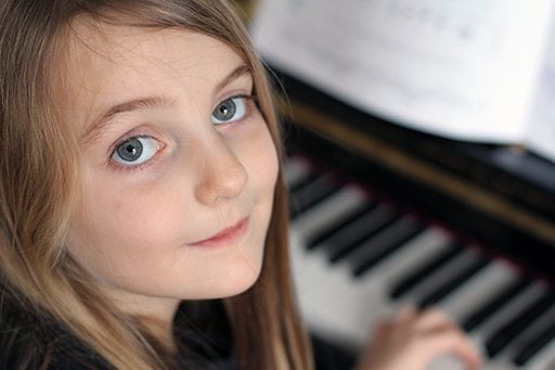 close up face of young girl with the piano on her background