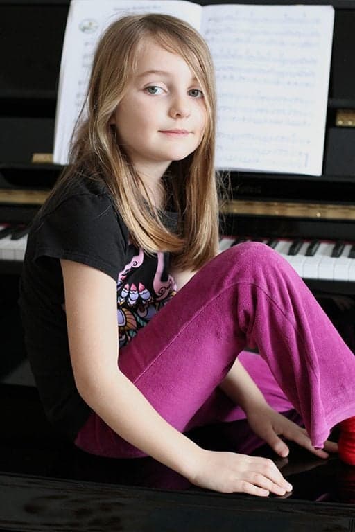 close up of young girl sitting in front of piano 