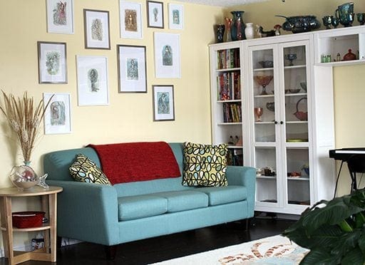 wall with framed art works, retro color couch and white shelving