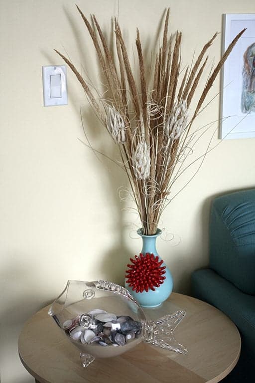 a vase and glass fish with seashells inside on the table