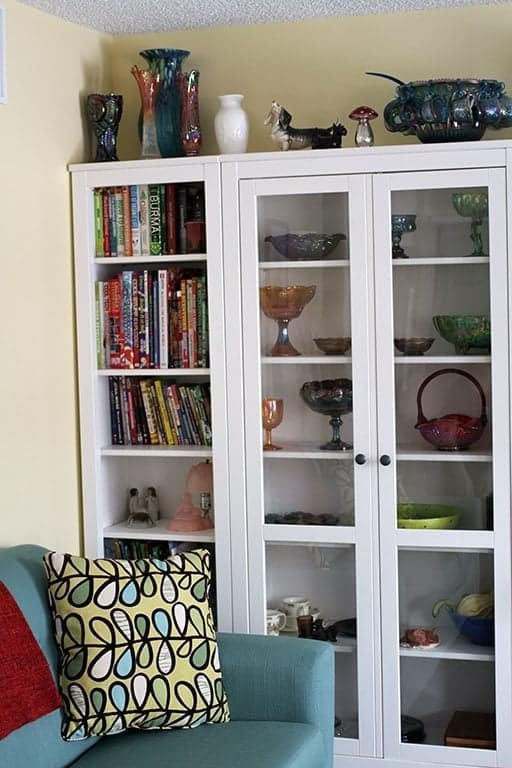 couch and white shelving with books and glasswares