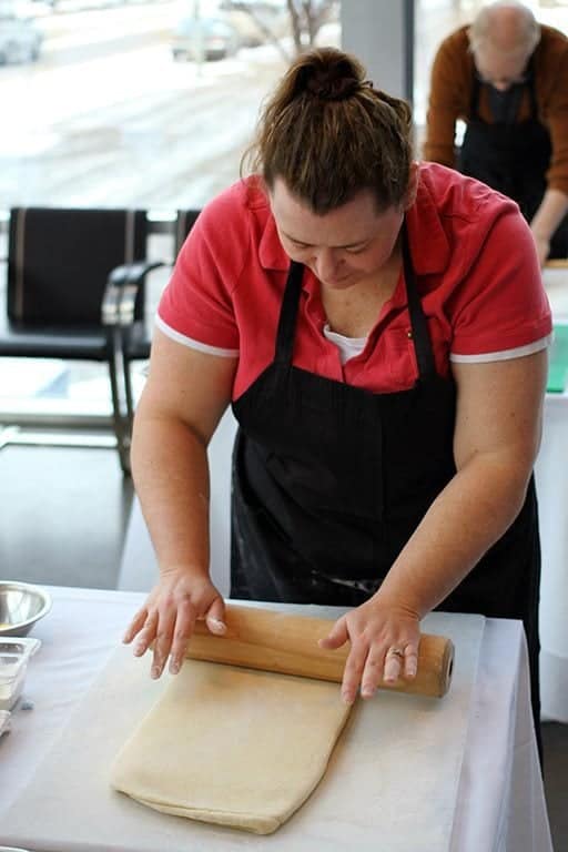 woman in red blouse rolling and folding the dough