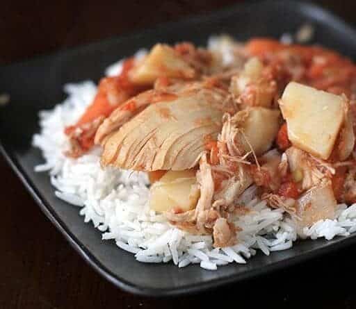 Chicken & Potato Stew on top of rice in a black plate bowl
